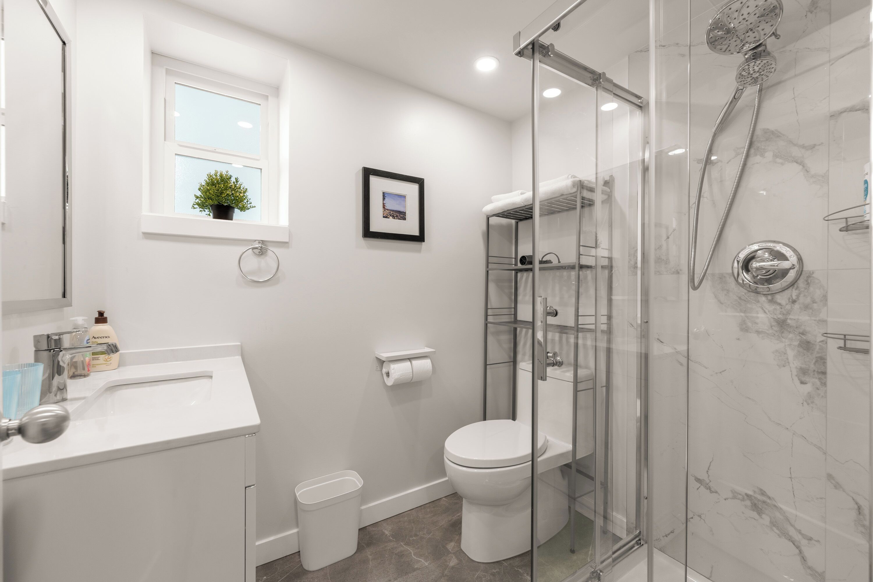 A modern bathroom with a glass-enclosed shower, a white sink, and a toilet.