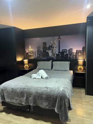 A modern hotel room with a city skyline view, a neatly made bed with towels, and two bedside lamps. - Cozy Loft with a Balcony in Campolim (Jardim America Sorocaba)
