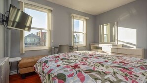 A bedroom with a large bed, two windows, a chair, a desk, and a mirror. - Chic 2-bedroom apartment (Brooklyn)
