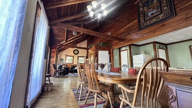 A wooden dining room with a chandelier, wooden chairs, and a large table.