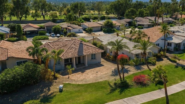 A residential area with houses, palm trees, and a well-maintained lawn. - Private Pool and Spa and Cooling Misting System (Palm Desert)