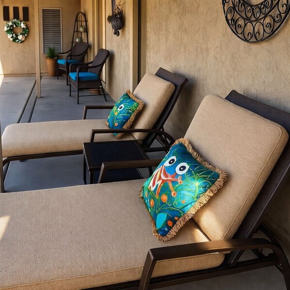A sunlit outdoor seating area with cushioned lounge chairs and decorative pillows.