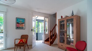 A spacious room with a wooden cabinet, wicker chairs, and a staircase leading to an outdoor area.