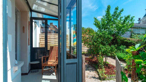 A glass door leading to a patio with a chair and a small table.