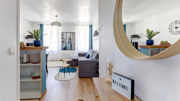 Una sala de estar moderna con un sofá, una mesa de centro y un comedor con una mesa y sillas de madera.