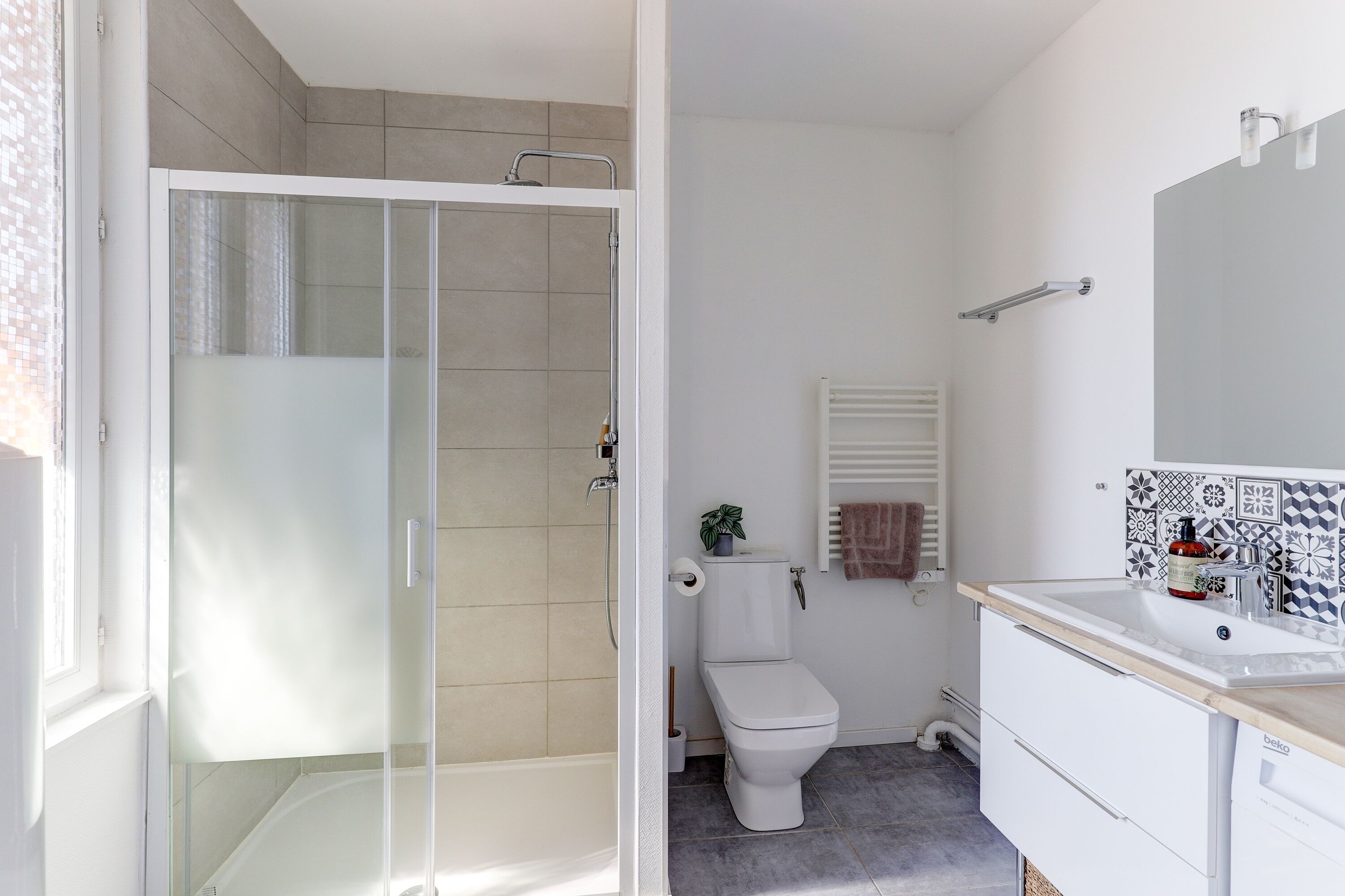 Uma casa de banho moderna com chuveiro em cabine de vidro, sanita e lavatório com espelho.