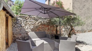 Un patio con muebles de mimbre y un paraguas grande.