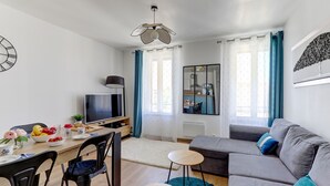Una sala de estar moderna con un sofá, televisión, mesa de comedor y un espejo grande.