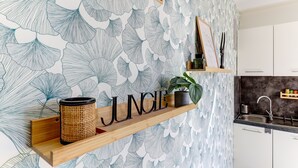 A kitchen with a wall-mounted shelf displaying a 'JUNGLE' sign, a woven container, and a potted plant. - Jungle d'orient - Proche centre ville Montluçon (Montlucon)
