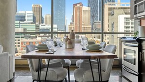 A modern kitchen with a dining area, large windows, and a city view.
