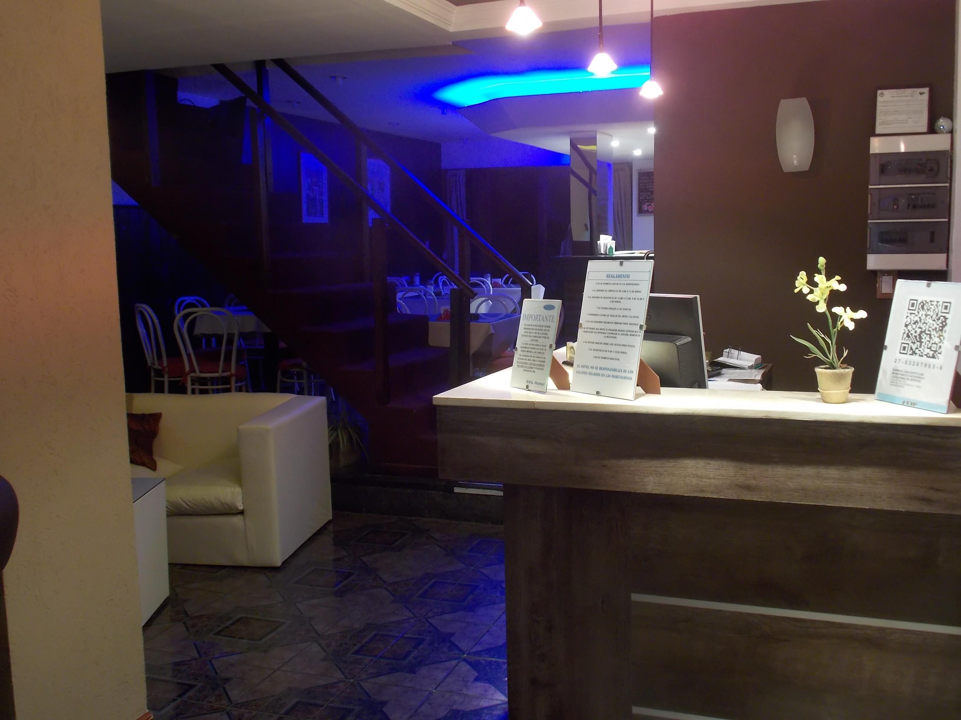 Ein Hotel-Rezeptionsbereich mit einem Holzbüro, einer Topf-Orchidee und einem Schild mit einem QR-Code.