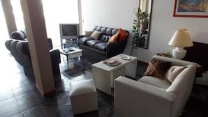 A modern living room with a sofa, armchairs, a coffee table, and a TV. - Hotel Sol (Mar del Plata)