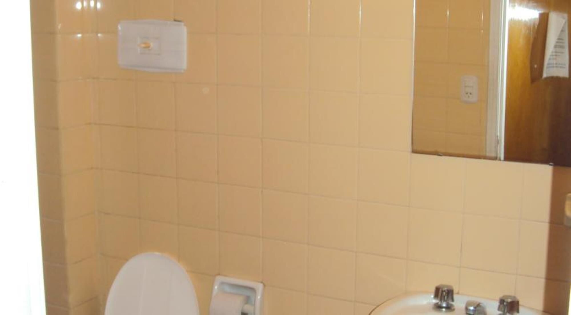 A bathroom with a toilet, sink, and mirror.