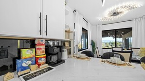 Una cuina moderna amb zona de cafè, incloent cafetera, tasses i un tauler per al cafè.
