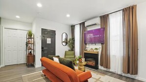 A modern living room with a sofa, a fireplace, a television, and a door.