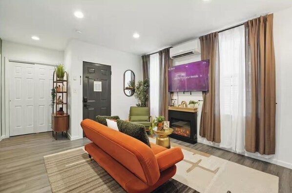 A modern living room with a sofa, a fireplace, a television, and a door.