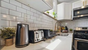 A modern kitchen with white subway tiles, stainless steel appliances, and a marble countertop.