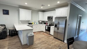 A modern kitchen with white cabinetry, a stainless steel refrigerator, a built-in oven, and a microwave.