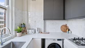 A compact kitchen with a washing machine, a toaster, and a kettle. - City Vibes in Darlinghurst (Darlinghurst)