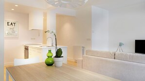 A modern kitchen with white cabinets, a sink, and a dining table with two vases.