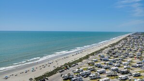 A beachside RV park with rows of RVs, a sandy beach, and the ocean. - Ocean-View Balcony: Resort Retreat in Myrtle Beach (Myrtle Beach)