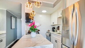 A modern kitchen with a marble island, stainless steel appliances, and a decorative plant. - Ocean-View Balcony: Resort Retreat in Myrtle Beach (Myrtle Beach)