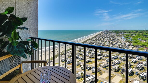 A balcony with a view of the beach and RV parking lot. - Ocean-View Balcony: Resort Retreat in Myrtle Beach (Myrtle Beach)