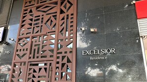 Een gevel met een decoratieve metalen poort en een bord waarop 'EXCELSIOR Residence' staat.