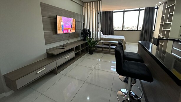 Een moderne hotelkamer met een flatscreen televisie, een bed, een zithoek en een groot raam.
