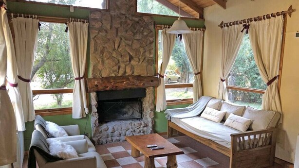 A cozy room with a stone fireplace, a sofa, a chair, and a wooden table.