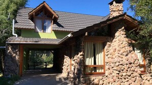 A stone house with a sloped roof, a chimney, and a wooden porch.
