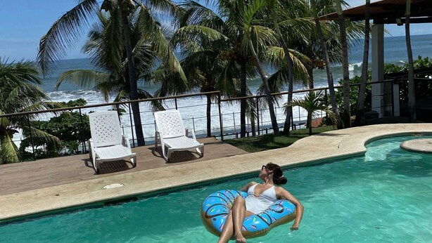 A pool area with clear blue water, lounge chairs, and palm trees. - El Tunco Beachfront Sirfcity Spot (La Libertad)