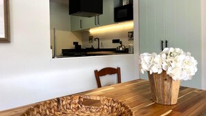 Eine moderne Küche mit integriertem Mikrowellenherd, einem Holzespeisetisch mit einem gewebten Korb und einer Vase mit weißen Blumen.