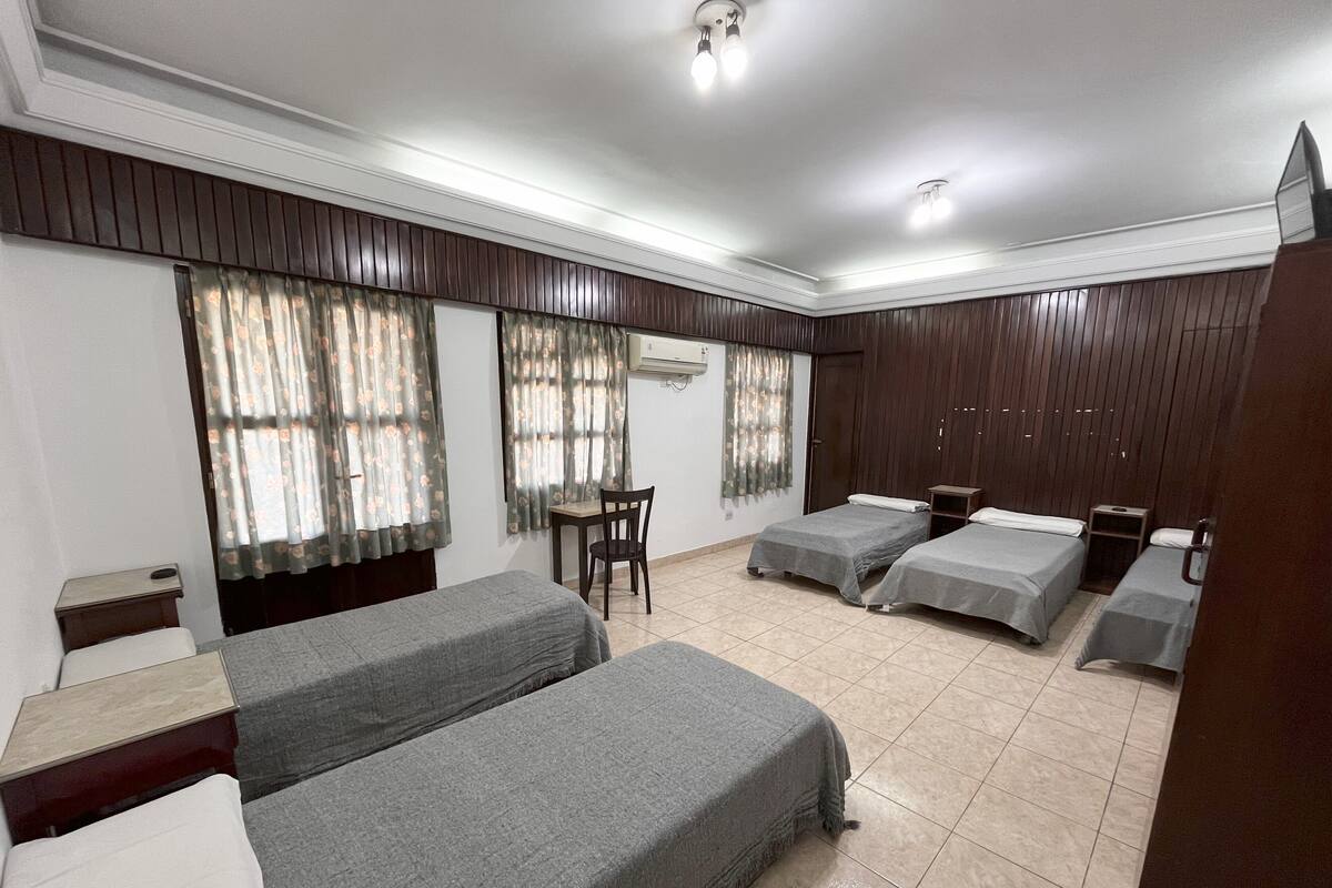 Ein Hotelzimmer mit zwei Einzelbetten, einem kleinen Tisch, einem Stuhl und einem Kleiderschrank.