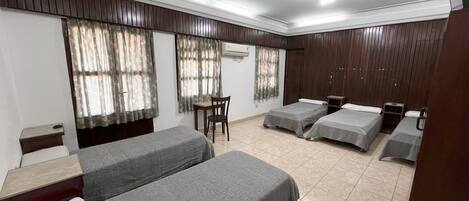 Una habitación de hotel con dos camas individuales, una mesita, una silla y un armario.