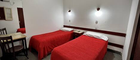 A hotel room with two single beds, a wooden chair, and a small table.