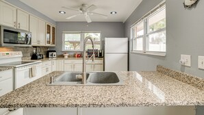 A kitchen with white cabinets, granite countertops, a stainless steel sink, a microwave, a stove, a refrigerator, and a ceiling fan. - 2 Mi to Riverwalk: Gem w/ Private Pool & Yard! (Bradenton)