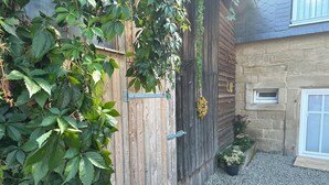 A wooden gate with a metal latch, a gravel pathway, and a small potted plant. - 60 sqm apartment on the ground floor with garden and courtyard for 2 people (Michelau in Oberfranken)