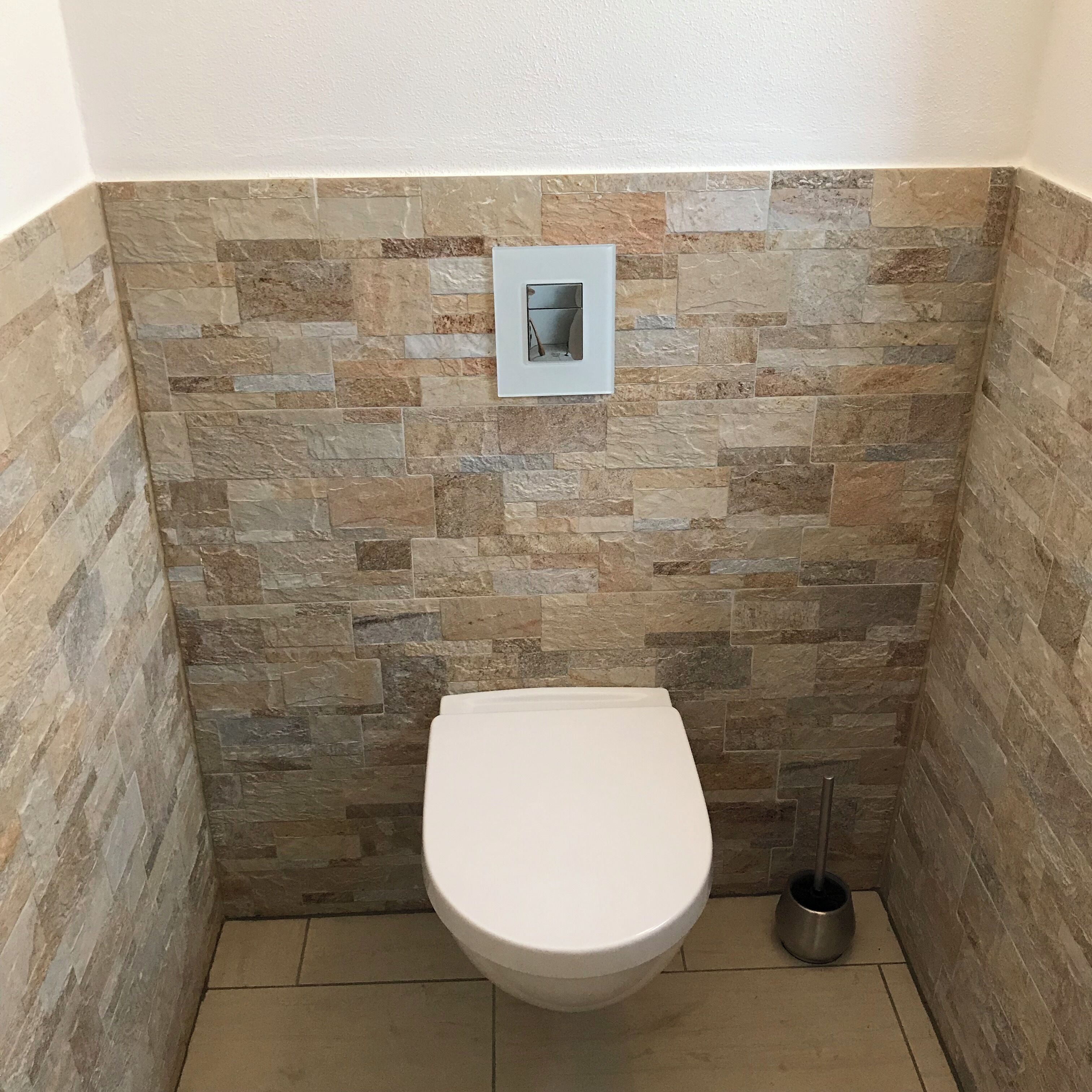 A small, tiled bathroom with a white toilet and a metal bidet.