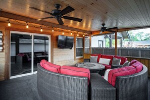 An outdoor patio with wicker furniture, ceiling fans, and string lights. - Hot Tub + Outdoor Kitchen: Stylish Home in Bryan (Bryan)