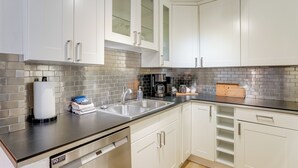 A modern kitchen with white cabinets, a stainless steel sink, and a black countertop. - < 1 Mi to Old Town: Scottsdale Condo w/ Balcony (Scottsdale)