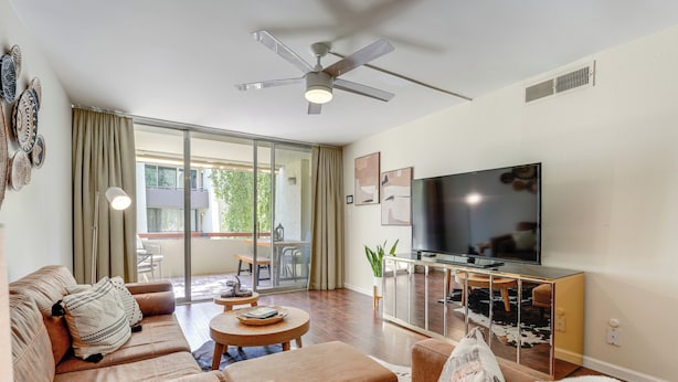 A modern living room with a sofa, coffee table, TV, and a ceiling fan. - < 1 Mi to Old Town: Scottsdale Condo w/ Balcony (Scottsdale)