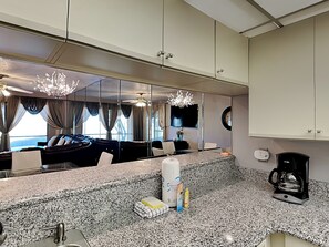 Una habitación de hotel moderna con un espejo grande, encimera de granito, una cafetera y un televisor.