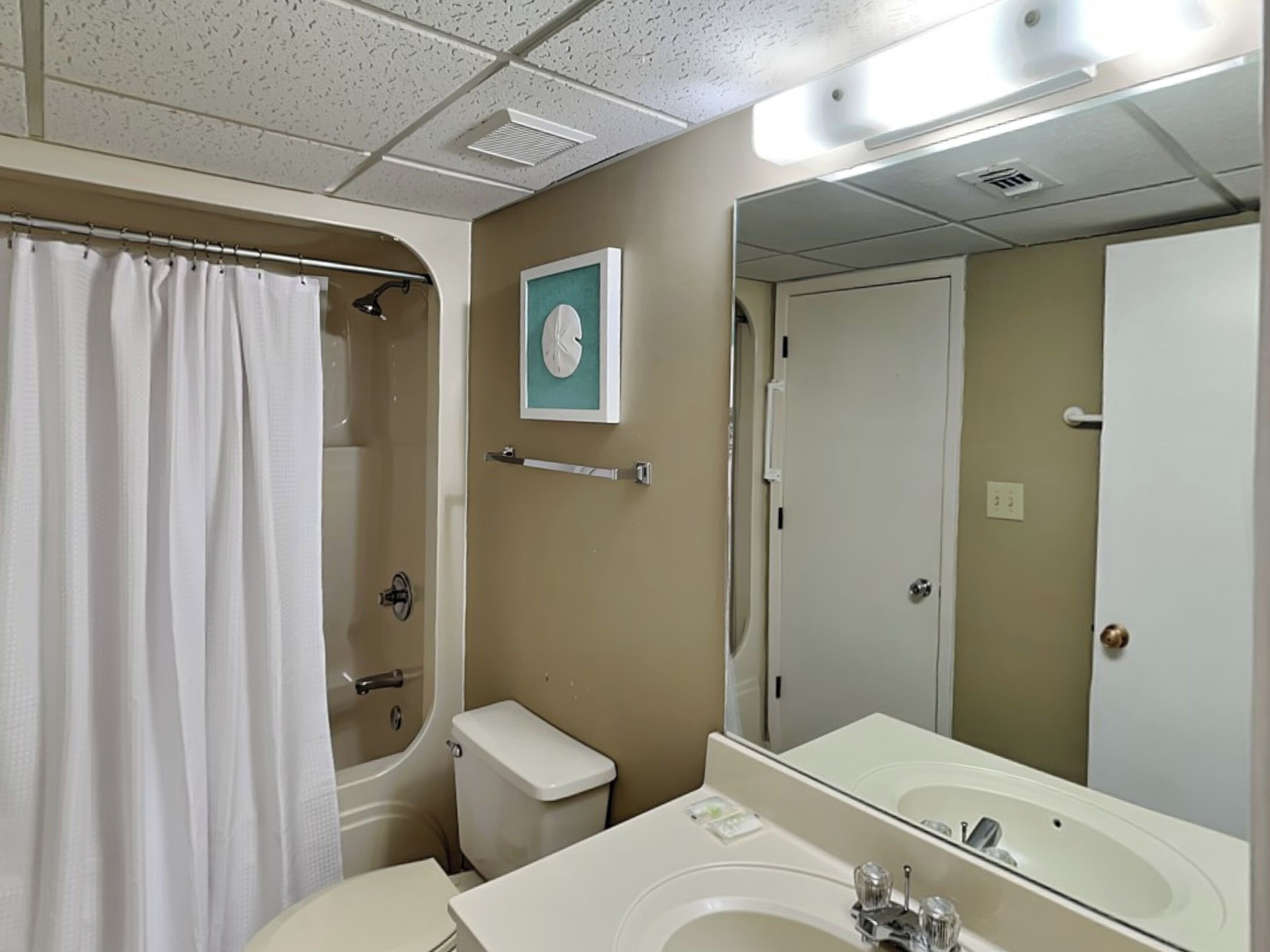 A bathroom with a shower, toilet, sink, and a mirror.