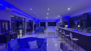 Ein modernes Wohnzimmer mit einem blauen Sofa und einem gestreiften Sessel, einer Bar mit Barhocker und einem großen Fenster.