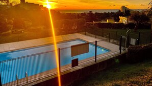 A swimming pool with a surrounding fence, a clear sky, and a sunset in the background. - Spicy love romantic suite - private jacuzzi - French Riviera - luxury (Villeneuve-Loubet)