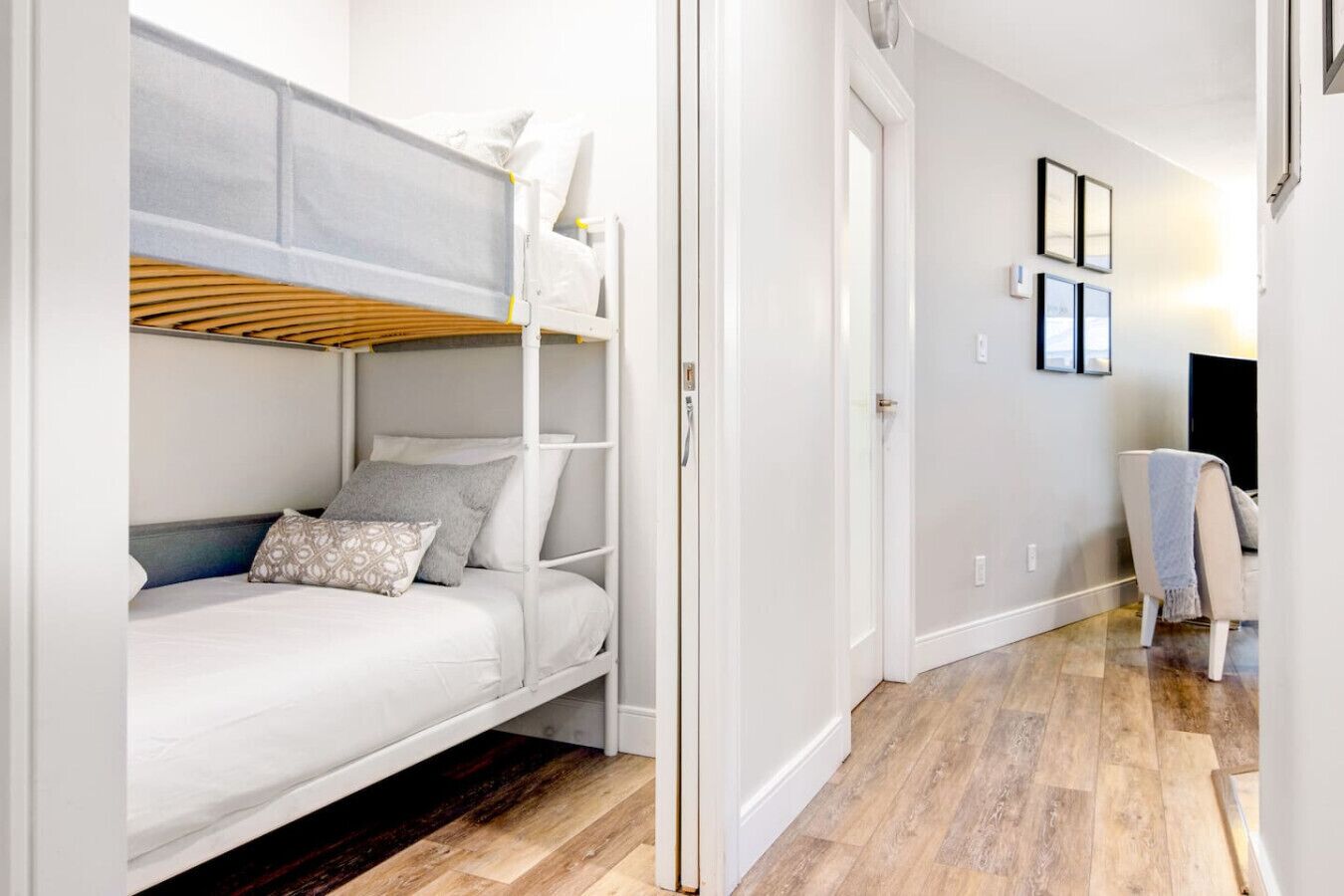 Una habitación con literas, una silla y una puerta que da a otra habitación.
