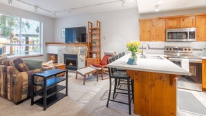 A modern kitchen with wooden cabinets, a central island, and stainless steel appliances. - Central Whistler Studio Townhouse|HotTub&Free PRKN (Whistler)