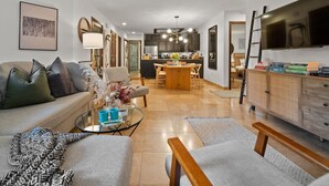 A modern living room with a sofa, coffee table, and a dining area with chairs and a table.