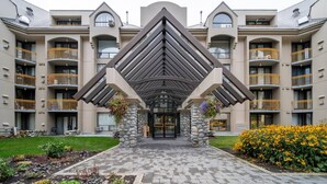 A multi-story hotel with a central entrance flanked by stone pillars and a geometric roof design. - Ski-in/Ski-out | Pool & Hot Tub | Sleeps 5! (Whistler)